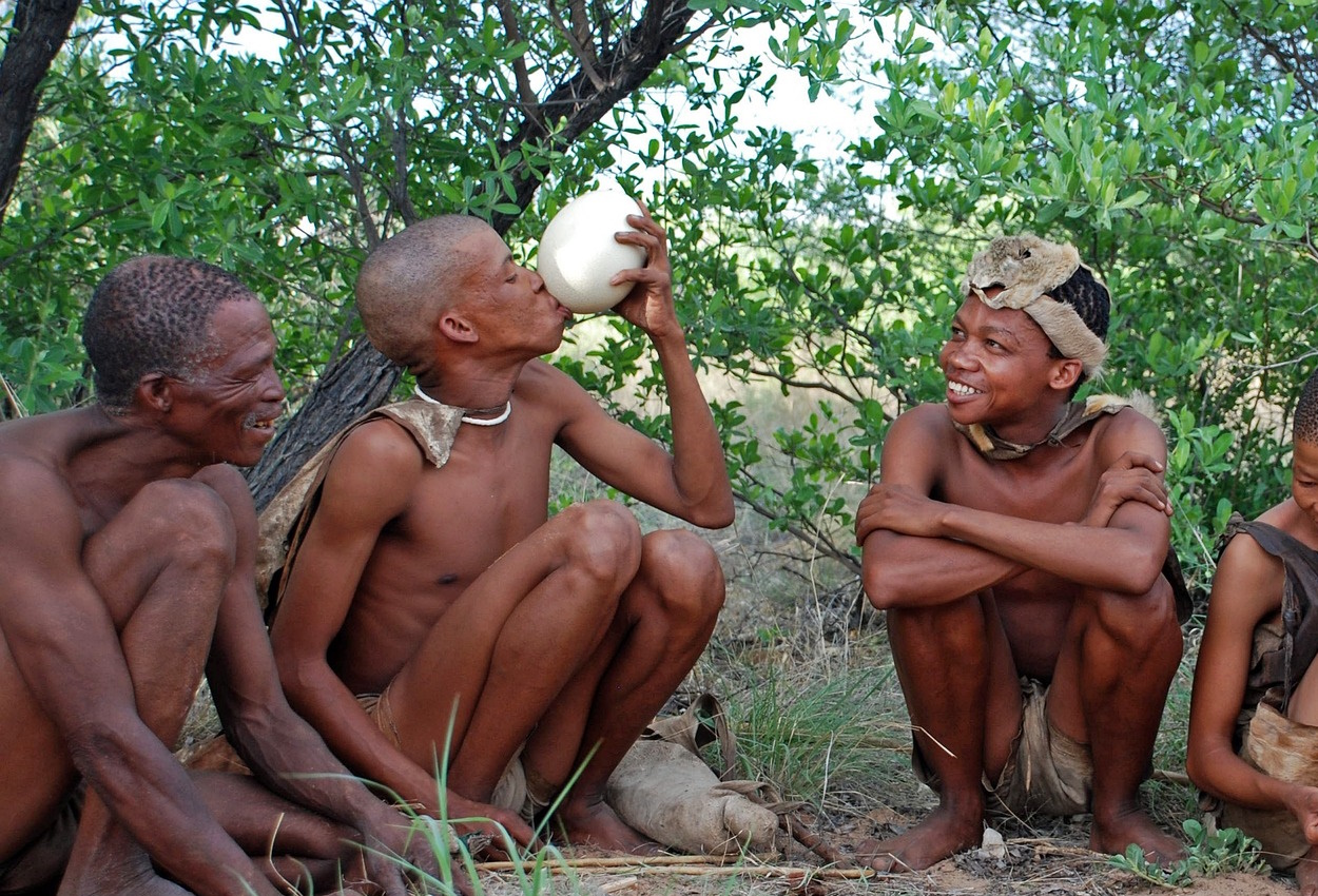 San people in traditional dress, Botswana landscape